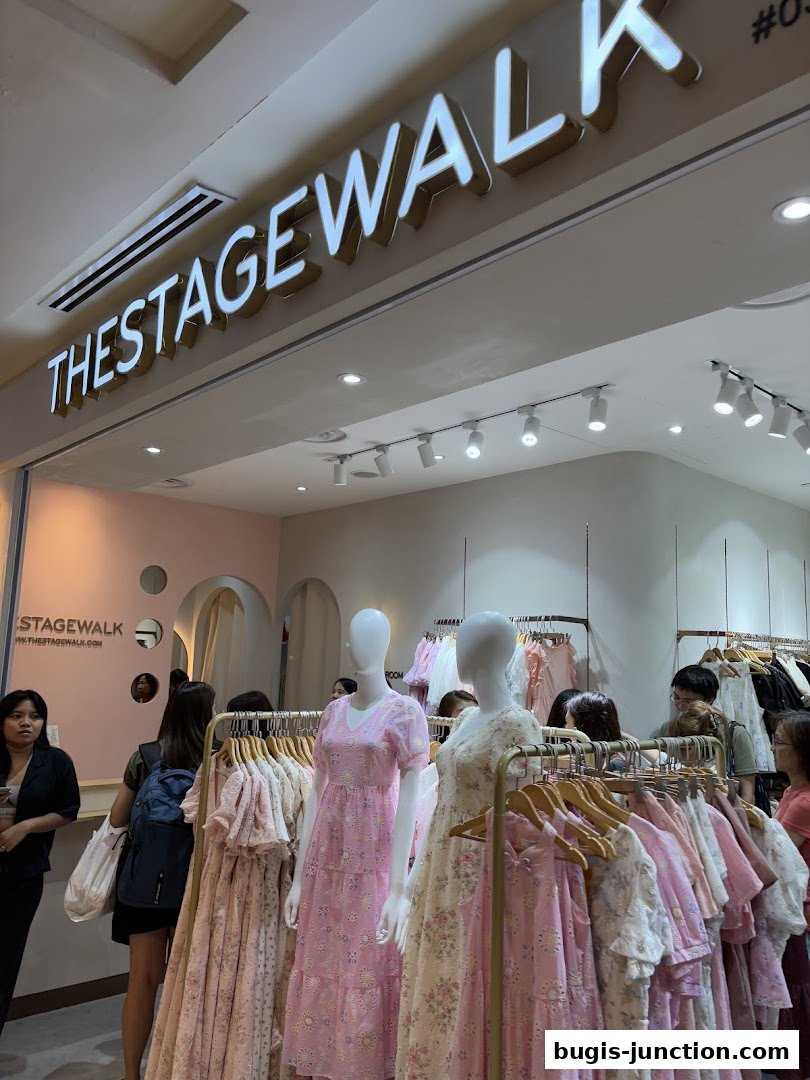 The Stage Walk shop front with mannequins displaying floral dresses and racks of clothing.