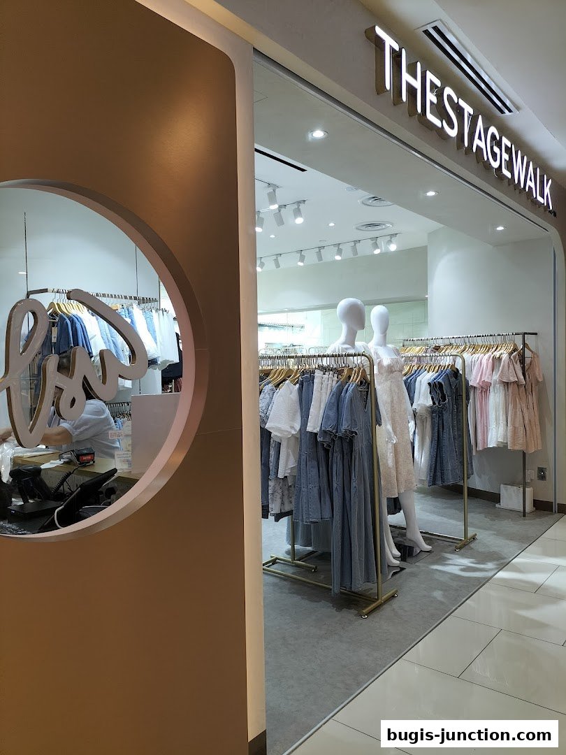 The entrance of a clothing store called The Stage Walk, displaying mannequins and racks of apparel.
