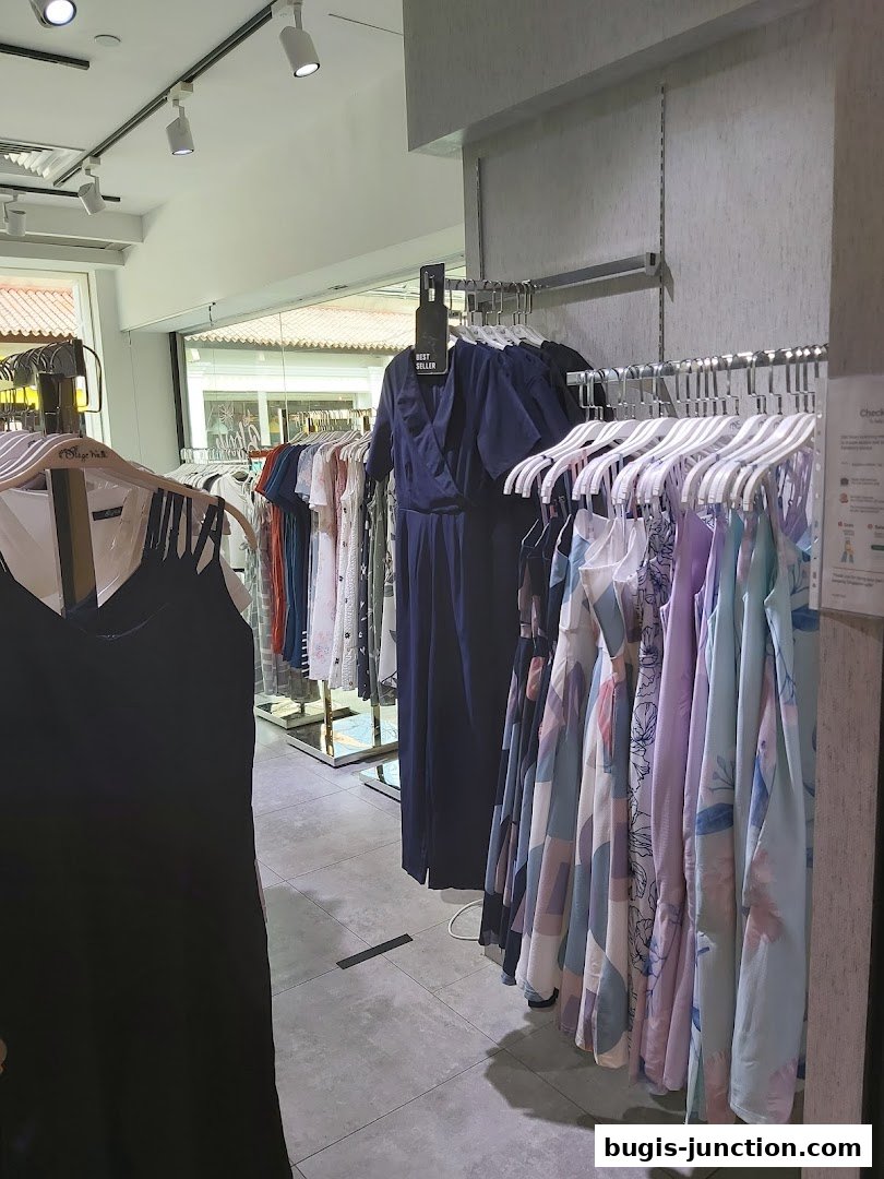 Interior view of a clothing store with racks of dresses and jumpsuits.