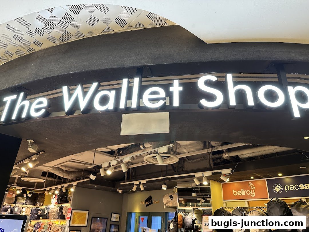 The illuminated sign for 'The Wallet Shop' is prominently displayed above a selection of bags and accessories.