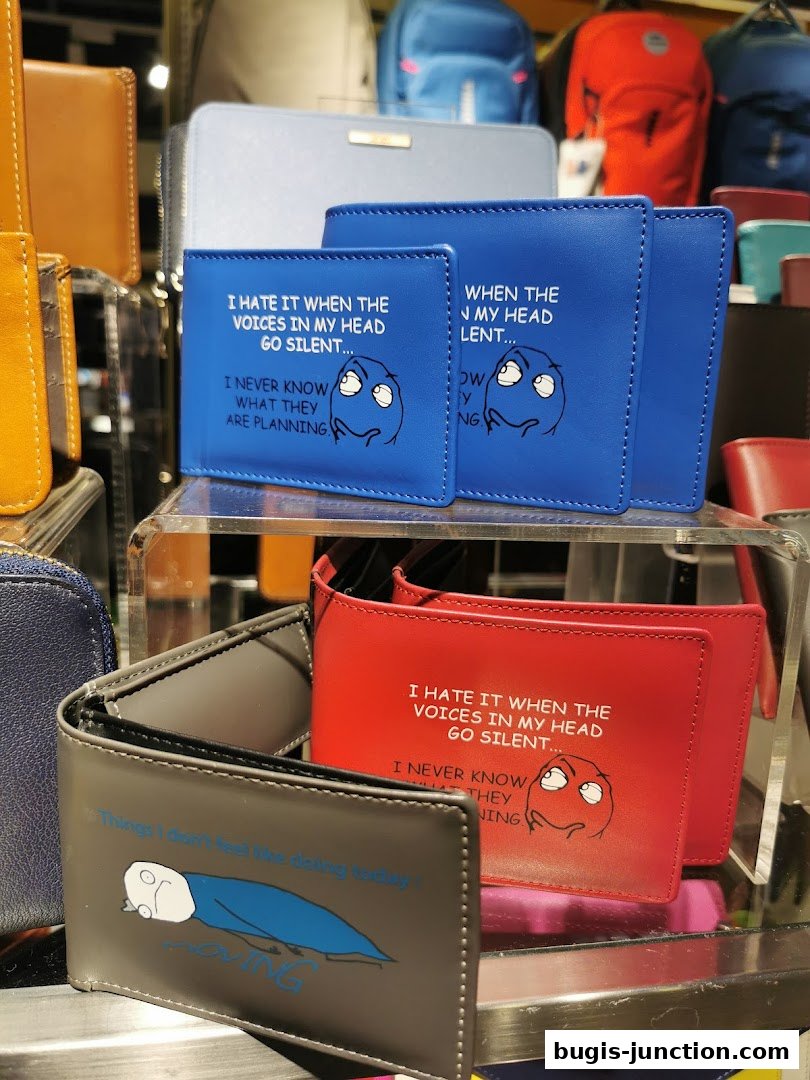 Wallets with humorous meme-style text and graphics displayed on shelves.
