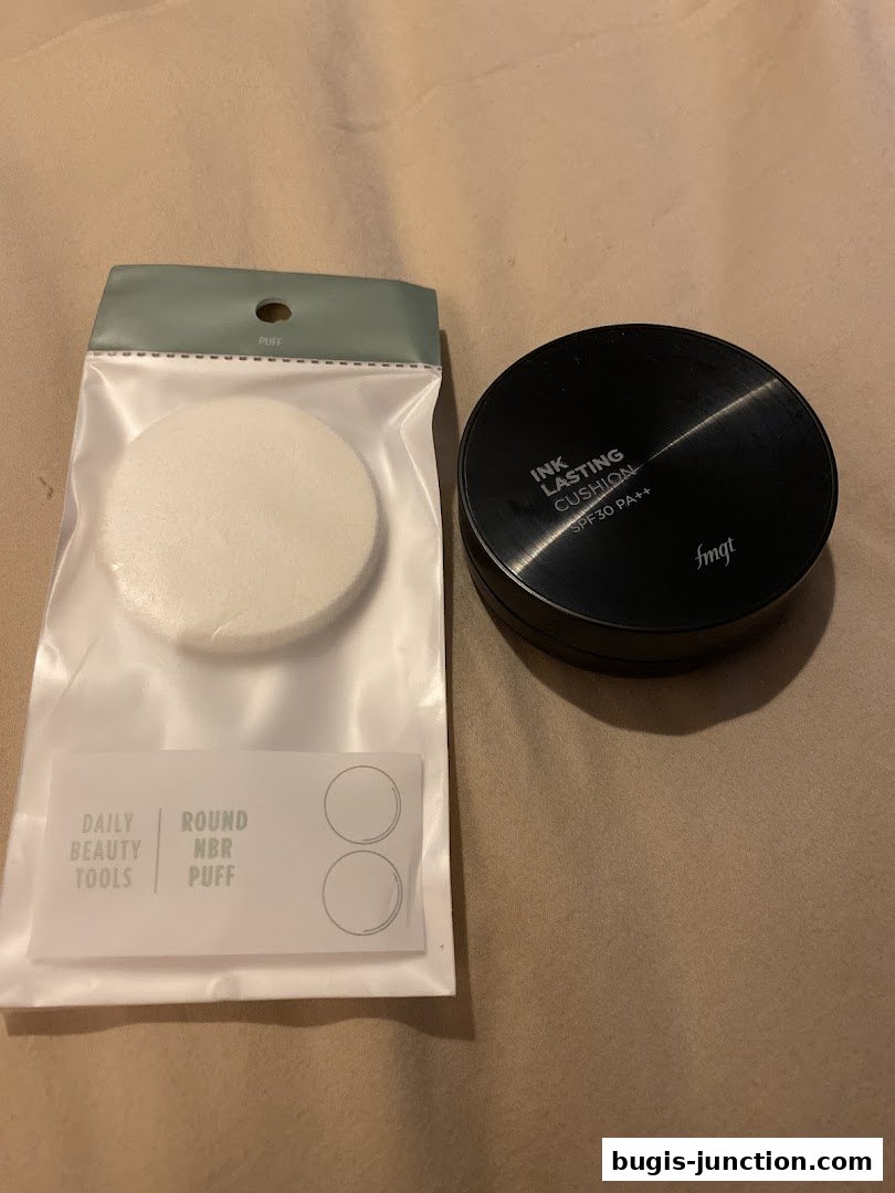 A black cushion foundation and a package of round makeup puffs from THEFACESHOP.