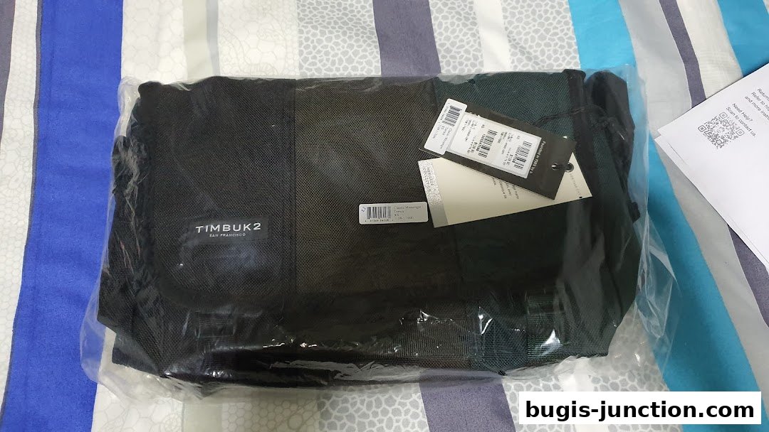 A Timbuk2 messenger bag in its original packaging with tags attached.