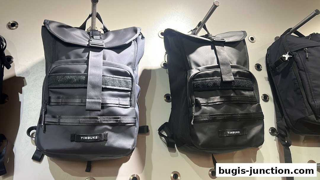 Two stylish black Timbuk2 backpacks are displayed on a wall.