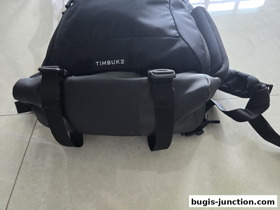 A close-up view of a black Timbuk2 backpack with adjustable straps and buckles.