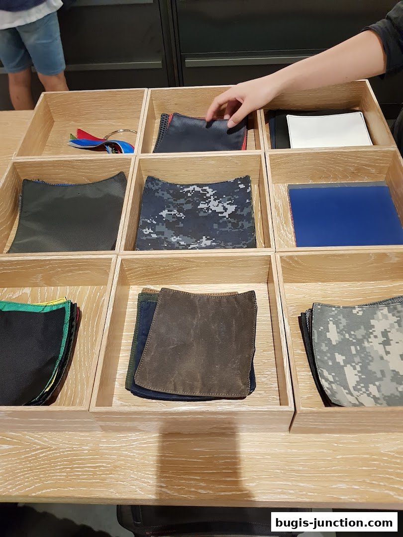 A display of various fabric swatches and accessories in wooden compartments.