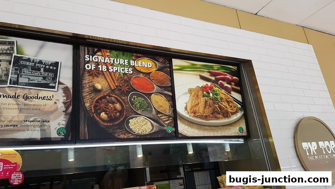 A display showcasing Tip Top Curry Puff's signature blend of 18 spices and a noodle dish.