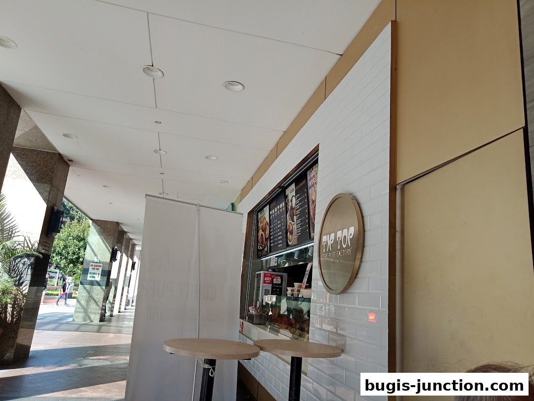 The exterior of Tip Top Curry Puff, a food stall with a menu and display of pastries.