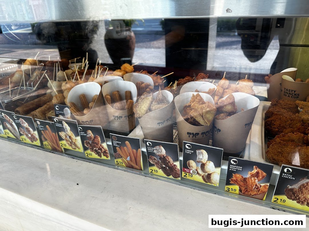 A display case filled with various fried snacks and skewers from Tip Top Curry Puff.