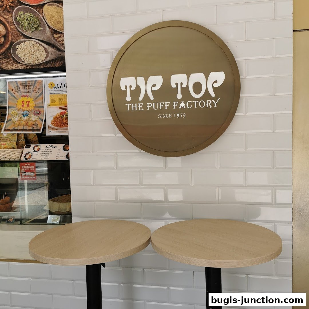 Interior shot of Tip Top Curry Puff with the shop's logo and seating area.