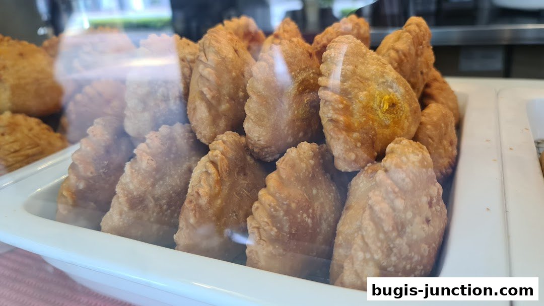 A close-up view of golden-brown curry puffs displayed in a white tray.