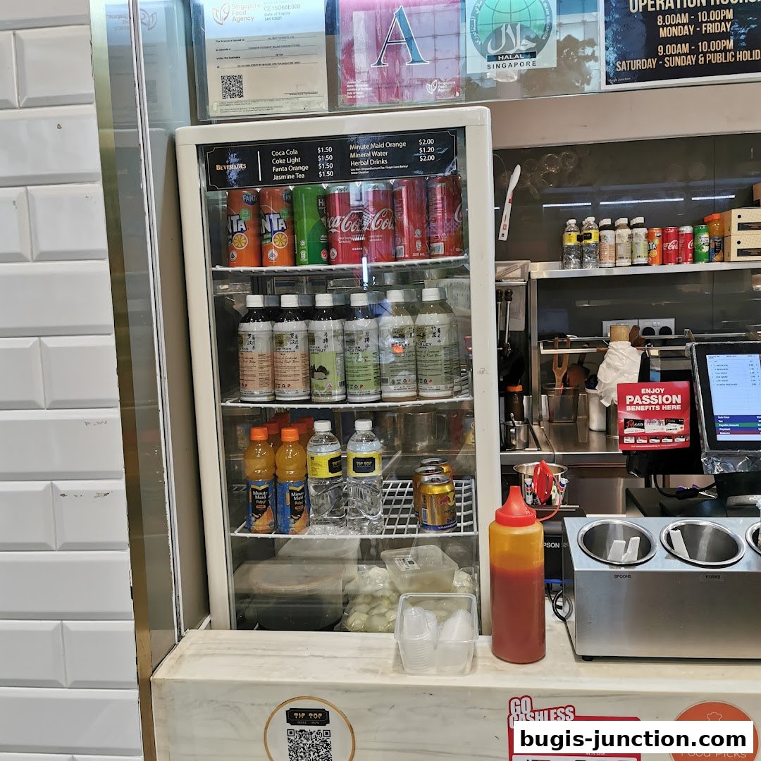 A display fridge filled with beverages and a counter with condiments and payment terminals.