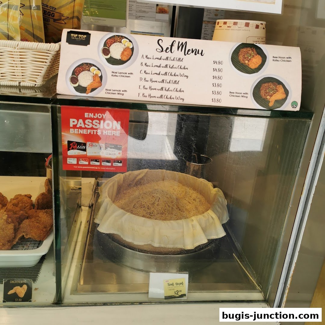 A display case featuring a set menu for Tip Top Curry Puff, with fried chicken and noodle dishes.