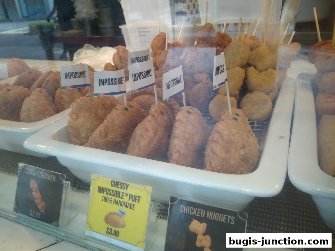 A display of fried snacks, including curry puffs and chicken nuggets, with 'Impossible' branding.