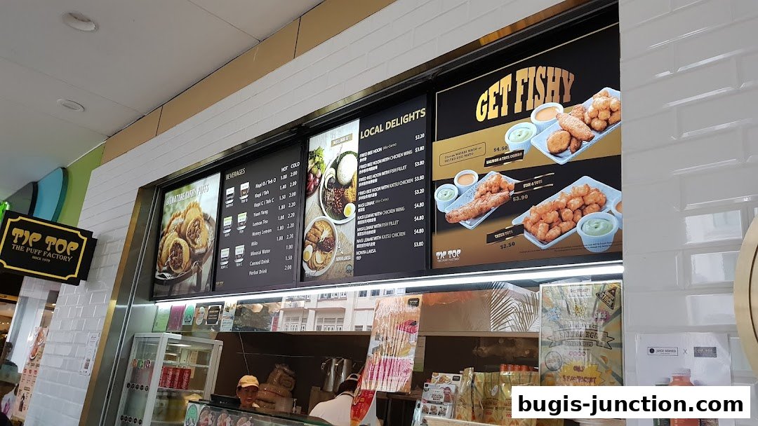 A menu board displaying various food and beverage options from Tip Top Curry Puff.