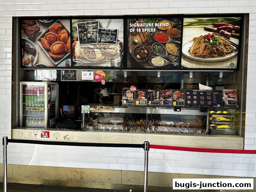 A display counter showcasing various curry puffs, snacks, and beverages at Tip Top Curry Puff.