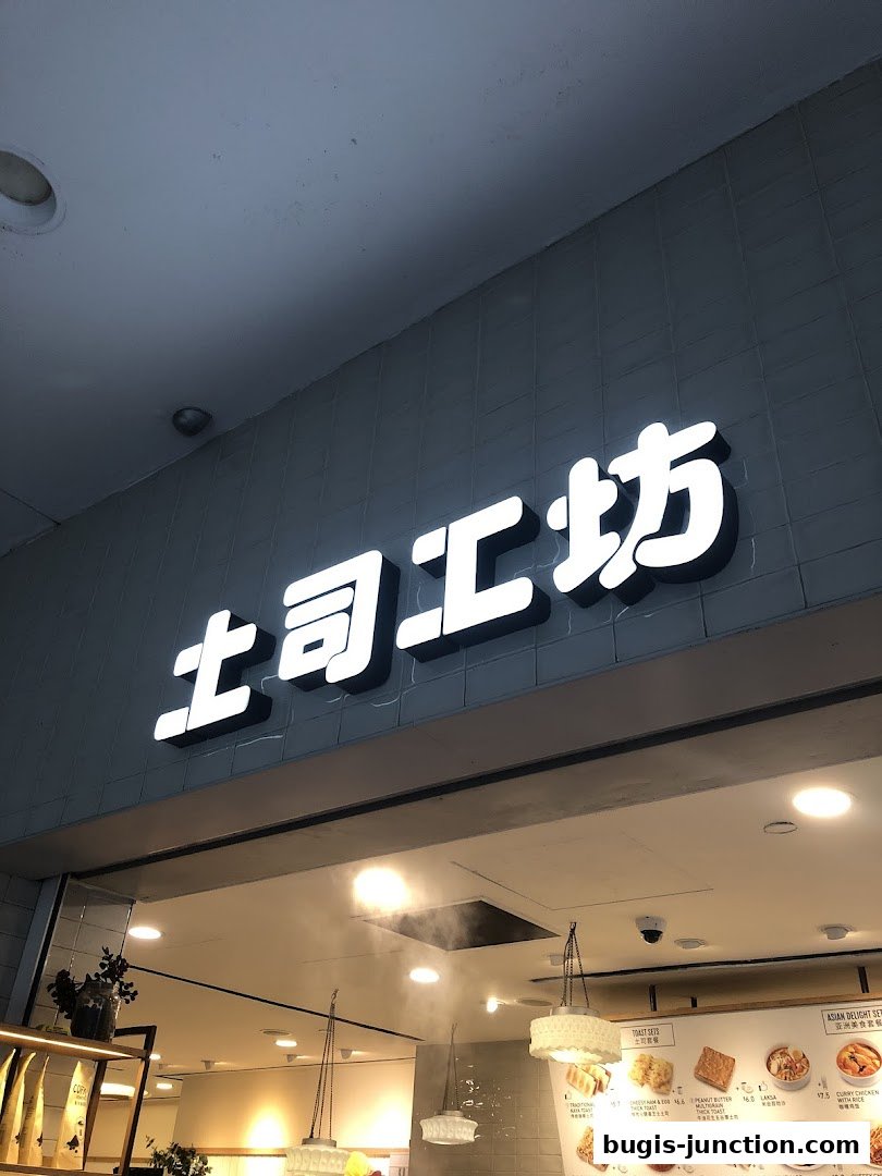 A brightly lit shop front with a prominent illuminated sign and a menu board displaying food items.