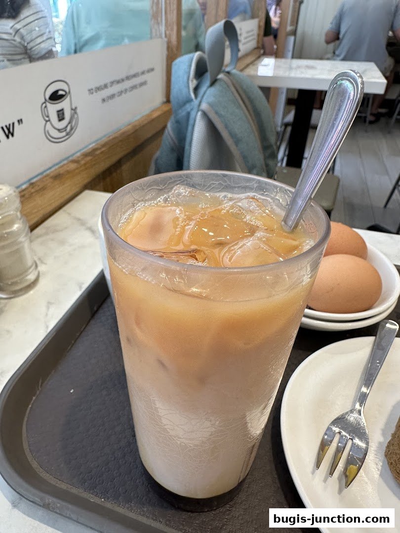 A refreshing iced coffee drink with a spoon and a side of boiled eggs.