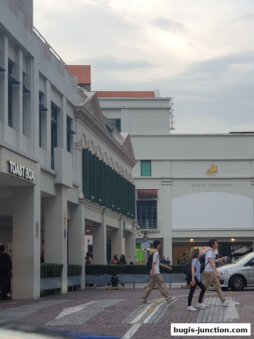 The exterior of Toast Box Bugis Junction with people crossing the street.