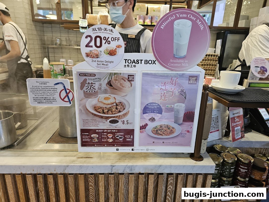 A display of food promotions and drinks at Toast Box, with staff in the background.