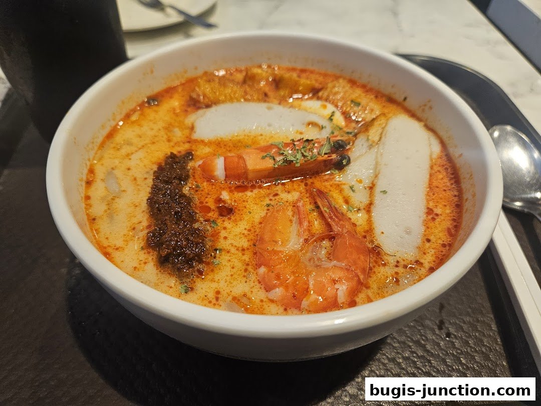 A close-up shot of a delicious bowl of Laksa with prawns and fish cake.