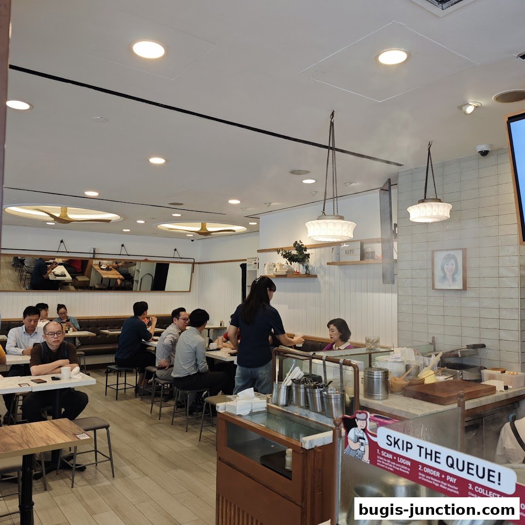 Customers dine inside a bright cafe with a server attending to a table.