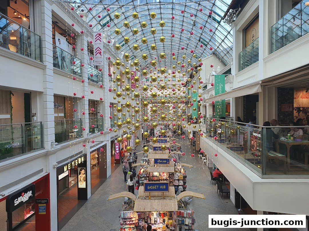 A wide shot of a shopping mall interior with festive decorations and various shops.