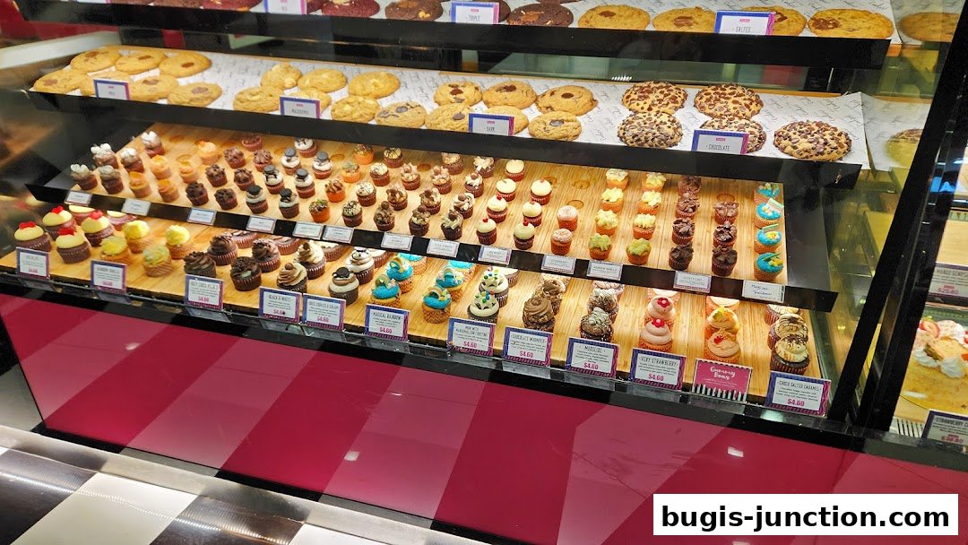 A display case filled with a variety of cupcakes and cookies, showcasing different flavors and toppings.
