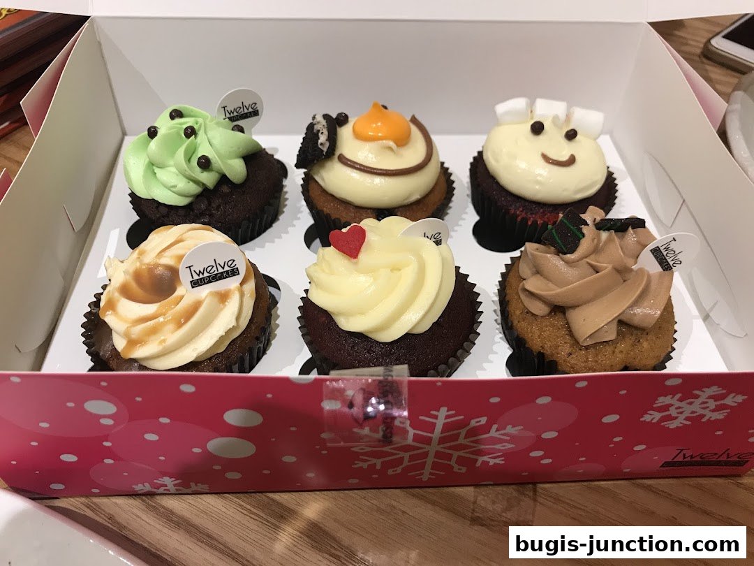 A box of six assorted cupcakes with colorful frosting and decorations.