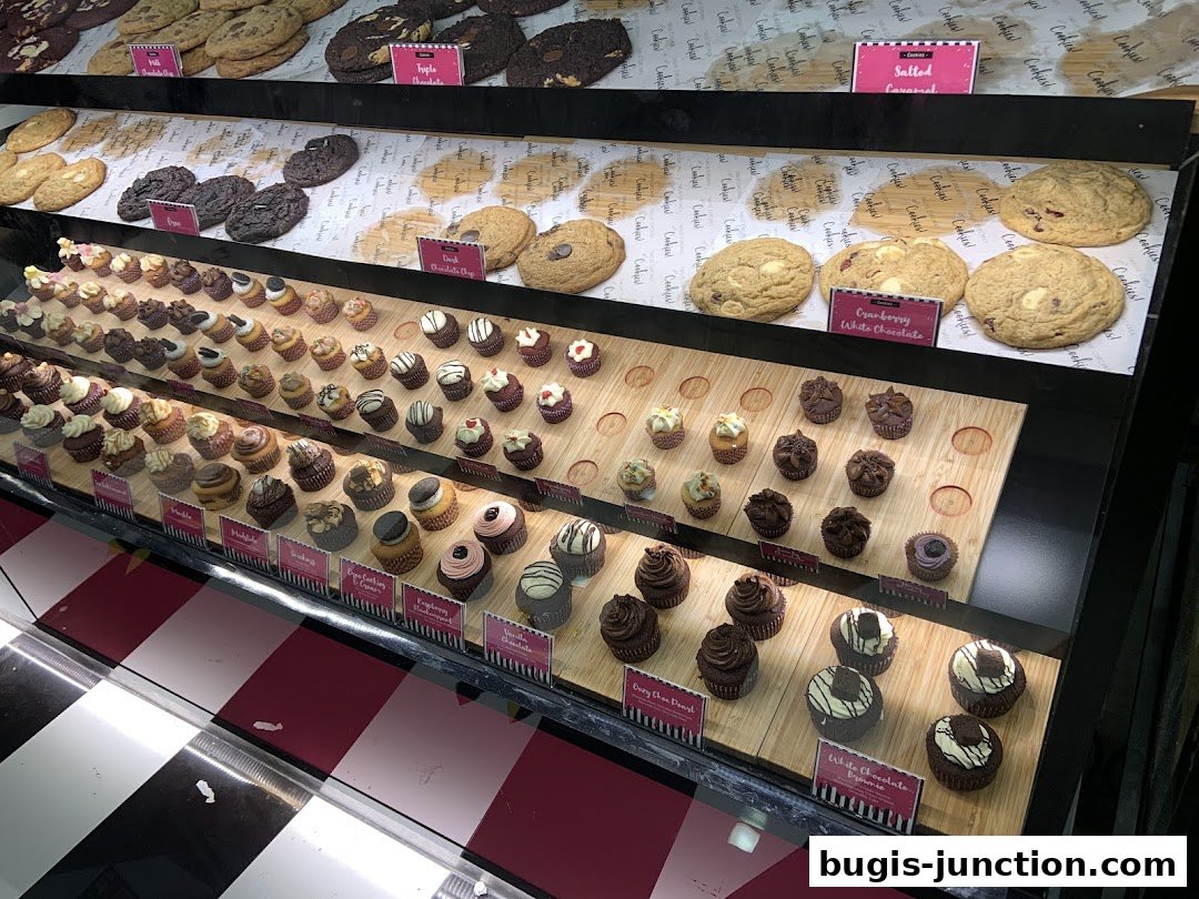 A display case filled with a variety of cupcakes and cookies from Twelve Cupcakes.