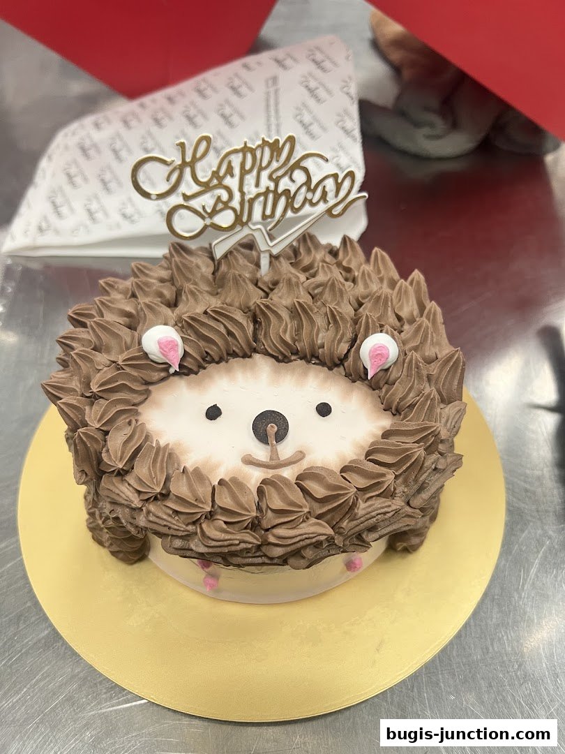 A cute hedgehog-shaped cake with chocolate frosting and a 'Happy Birthday' topper.