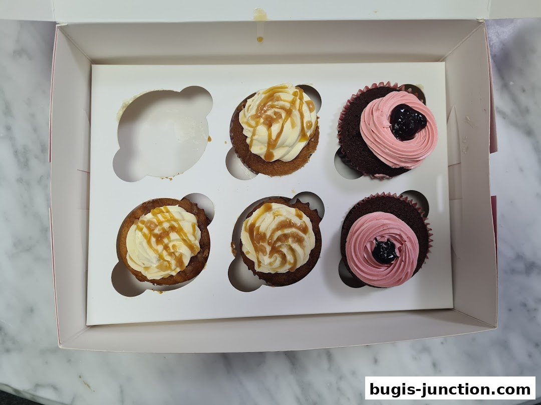 A box of six cupcakes, with three caramel-frosted and three pink-frosted cupcakes.