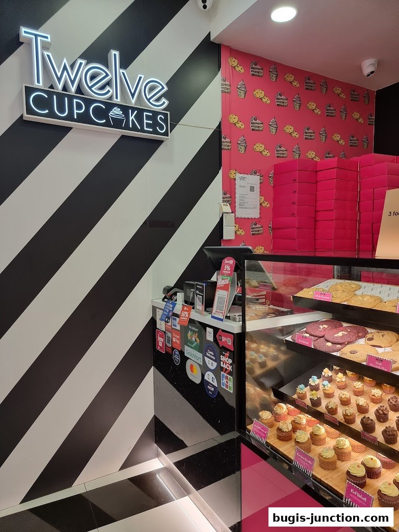 A display case filled with cupcakes and cookies at Twelve Cupcakes shop.