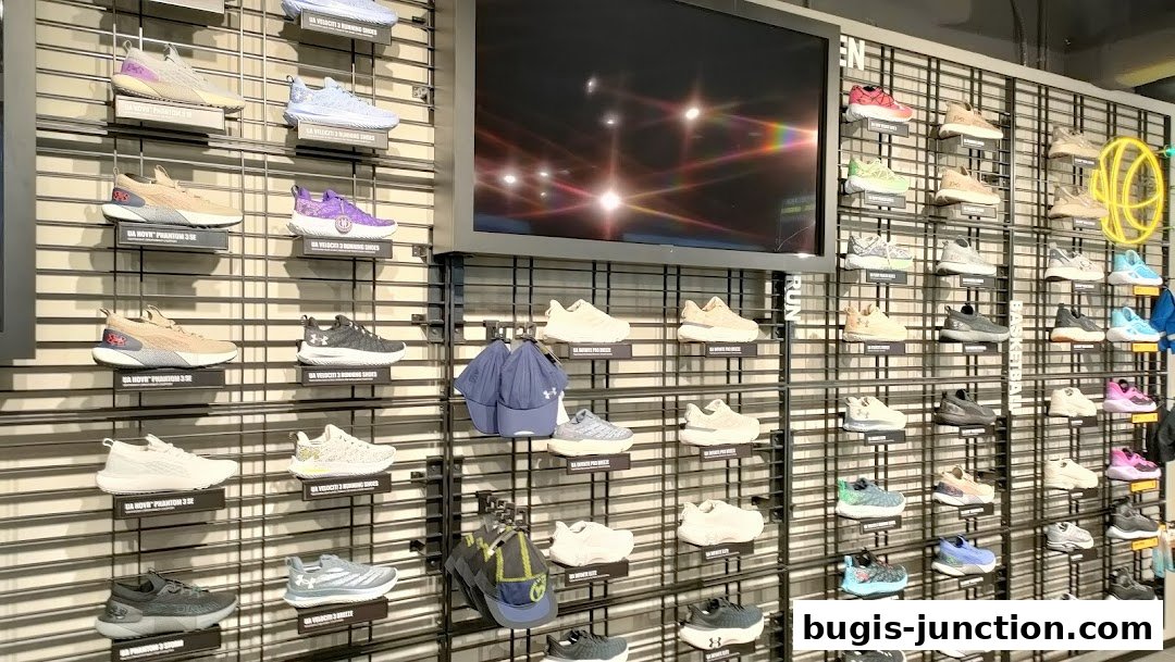 Wall display of Under Armour running and basketball shoes, along with caps.