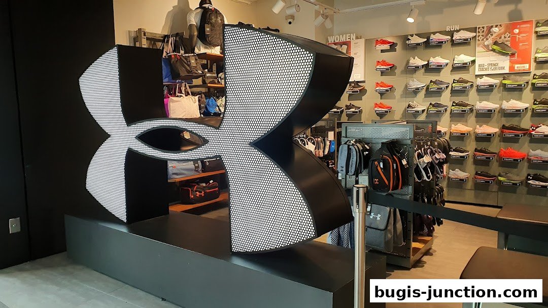 Interior of an Under Armour store featuring a large logo and displays of shoes and bags.