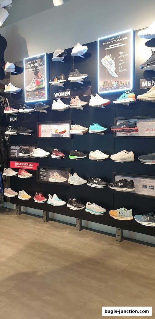 A wall display showcasing a variety of Under Armour running shoes for men and women.