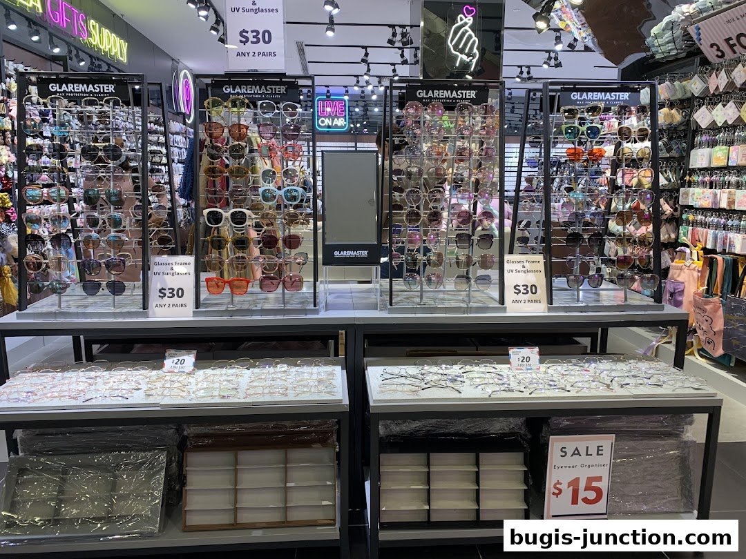 A retail shop displaying a wide selection of sunglasses and eyeglasses, with promotional signs.