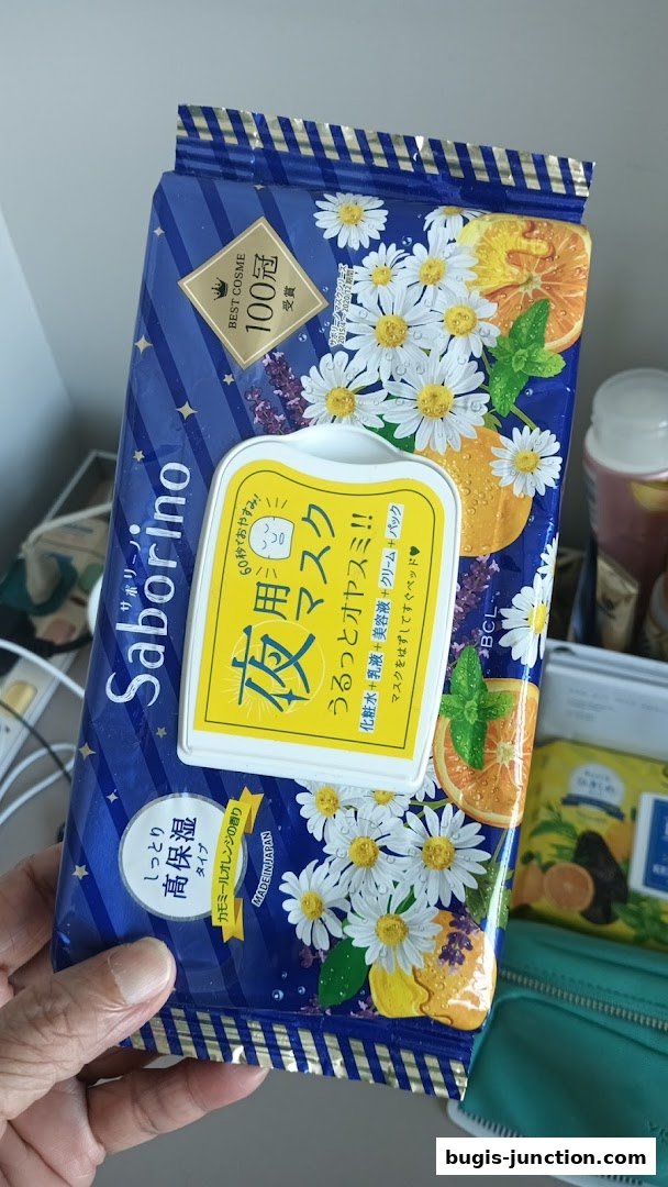 A hand holds a Saborino night mask package with chamomile and orange design.