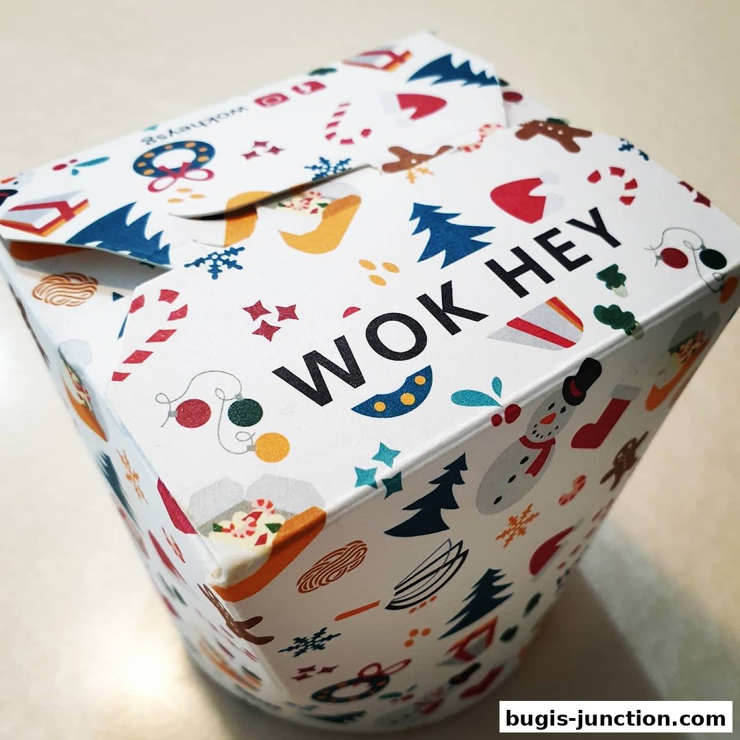 A festive Wok Hey takeaway box with holiday-themed illustrations and the brand name.