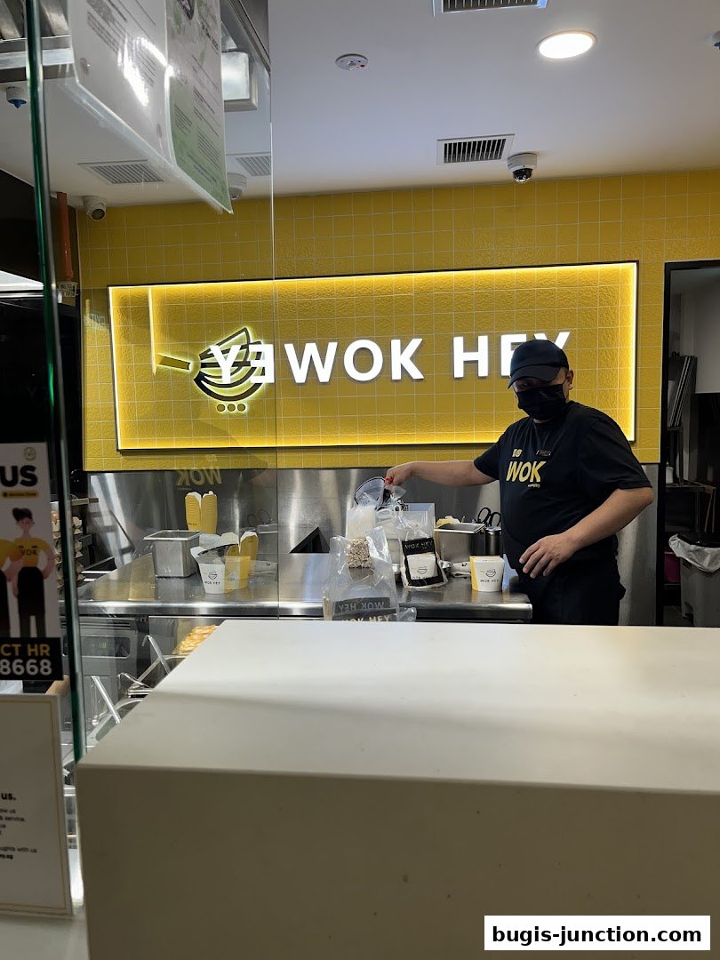 A staff member at Wok Hey Bugis Junction prepares an order behind the counter.