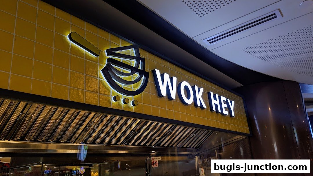 The illuminated WOK HEY sign is displayed prominently on a yellow tiled wall.