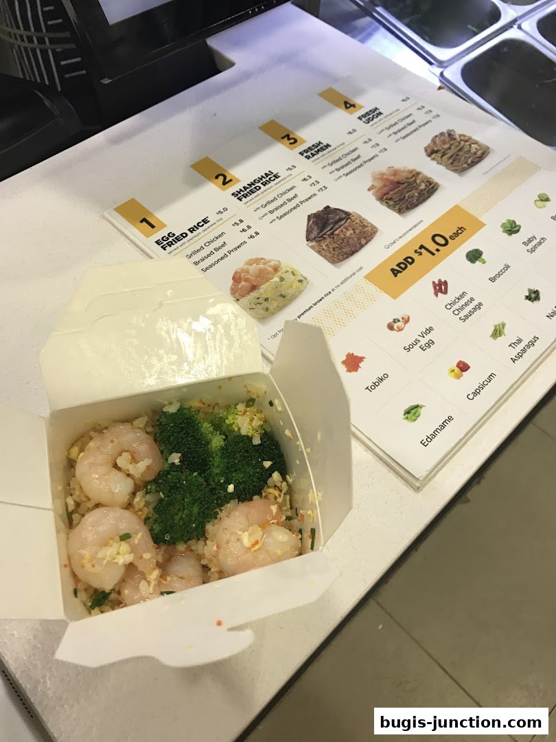 A takeout box of fried rice with shrimp and broccoli next to a menu.
