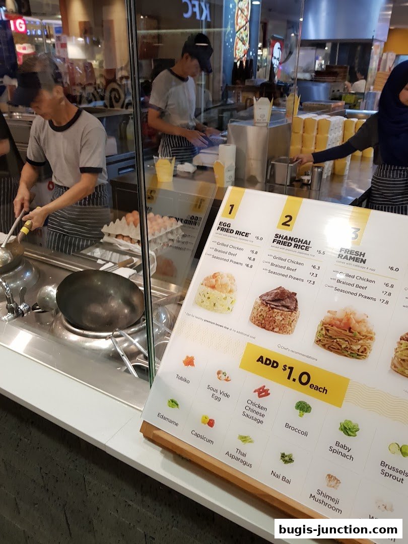 A menu board displays various rice and ramen dishes with add-on options.