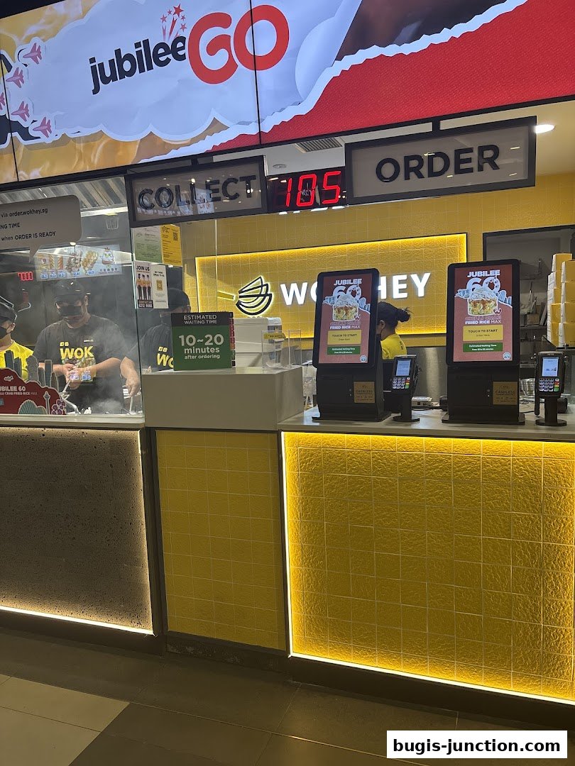 The WOK HEY Bugis Junction shop front with digital displays and ordering kiosks.