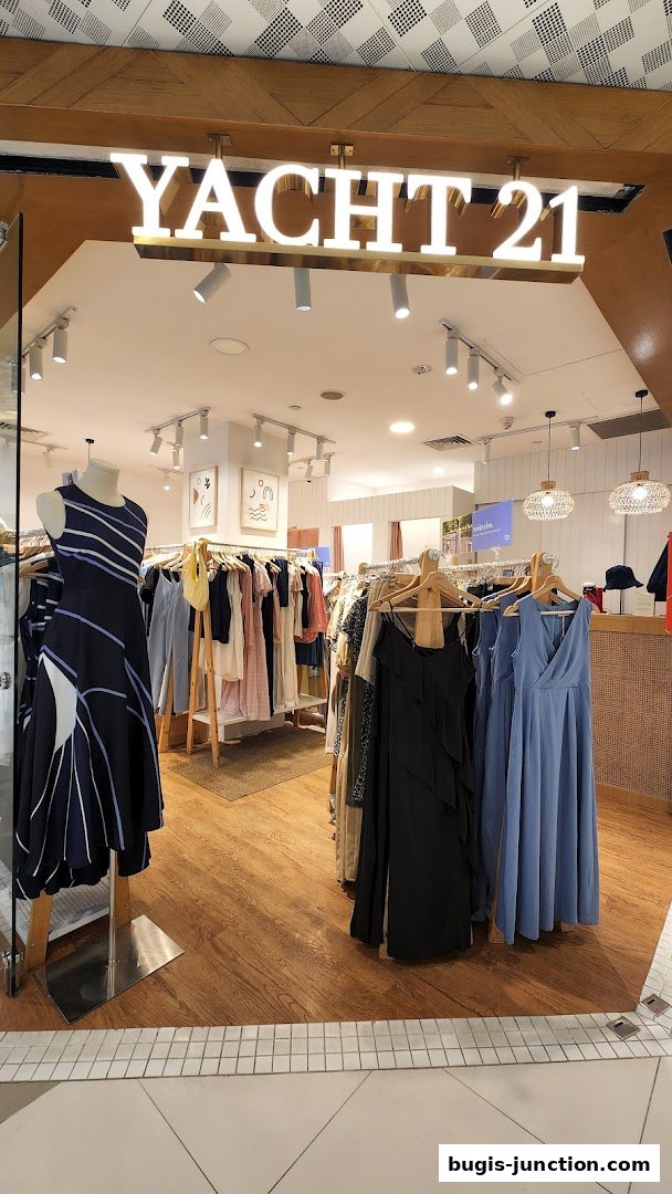 The entrance of Yacht 21 clothing store, showcasing dresses and apparel on display.