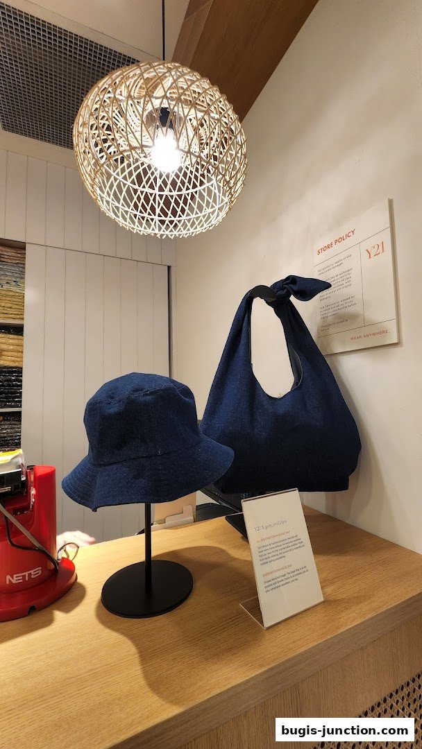 Y21 Bugis Junction displays denim bucket hat and tote bag with store policy sign.