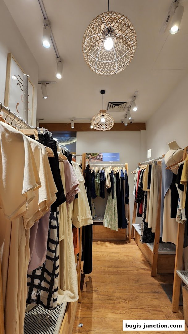 Interior view of a clothing store with racks of apparel and decorative lighting.