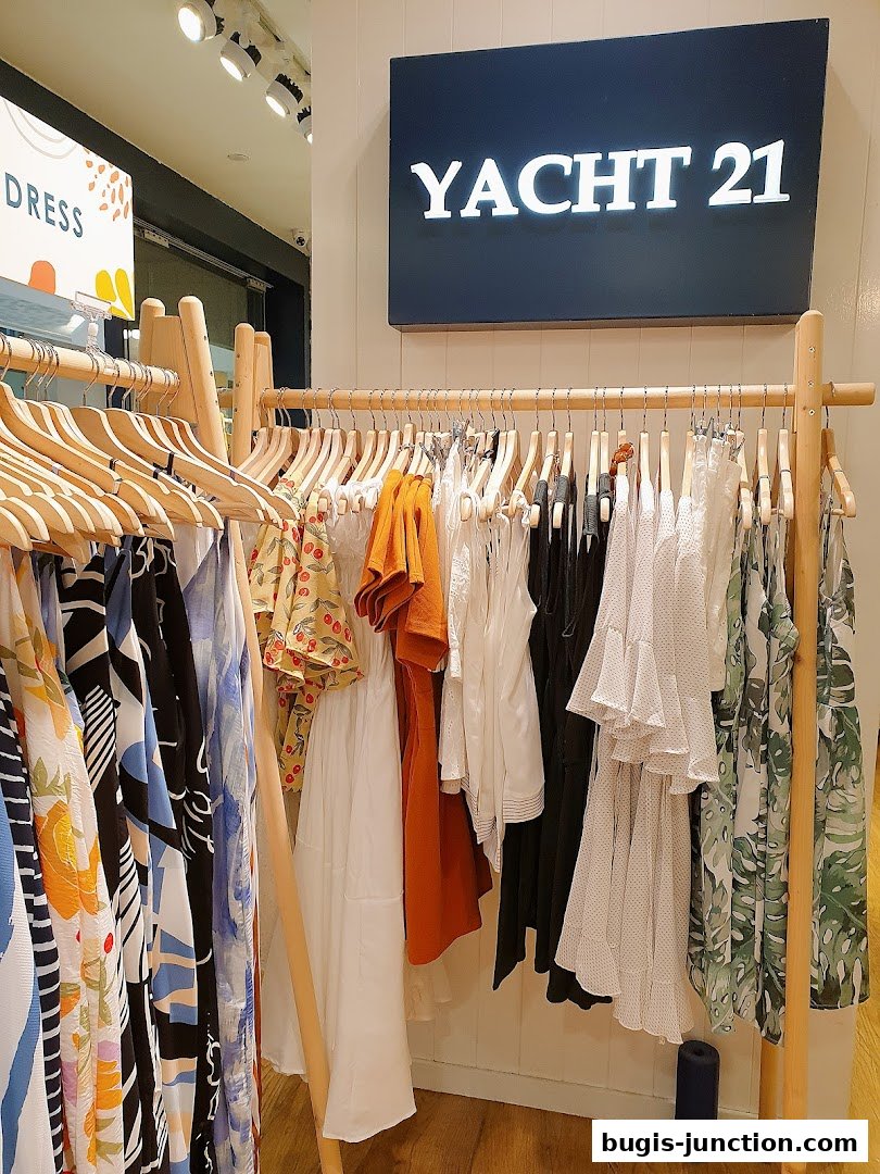 A clothing rack displaying various dresses and tops from Yacht 21.