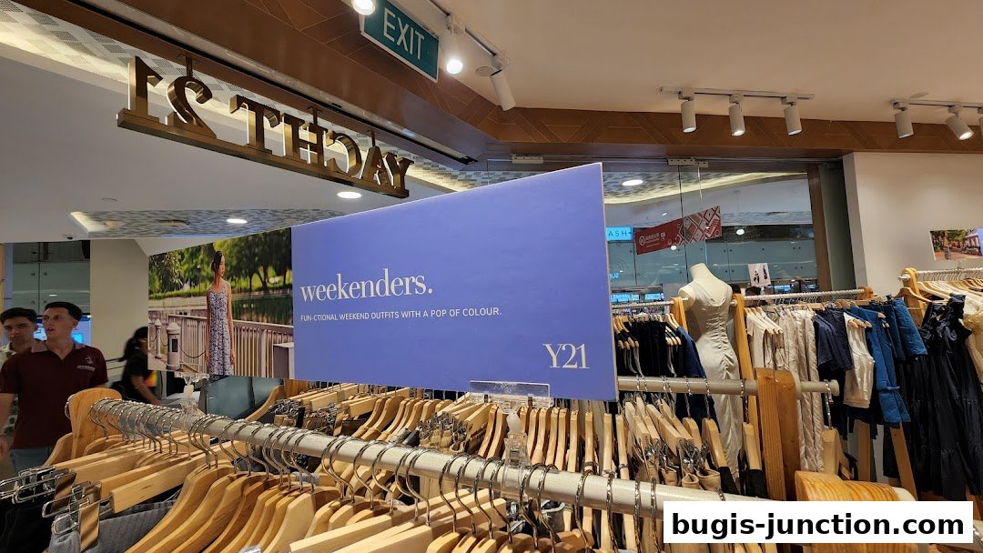 A clothing store interior with racks of clothes and a promotional sign for 'weekenders'.