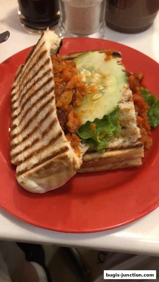 A close-up shot of a grilled sandwich with cucumber and lettuce on a red plate.